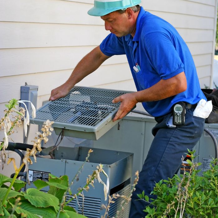 An hvac technician installing a new ac unit on the outside of a house