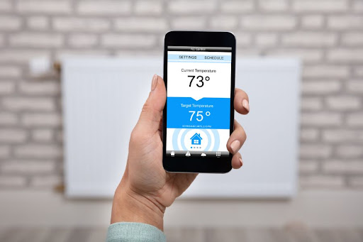 A hand holding up an phone displaying all temperature controls for the home