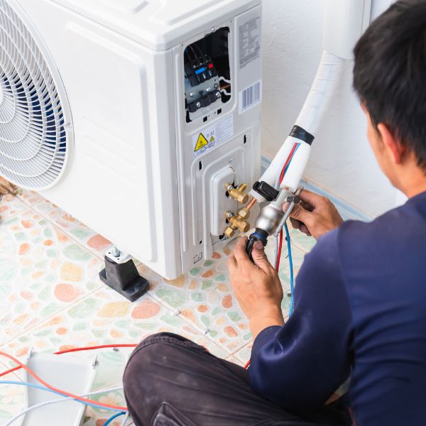 A precision air employee checking the hoses of a ductless mini-split on the exterior of a customer's home.